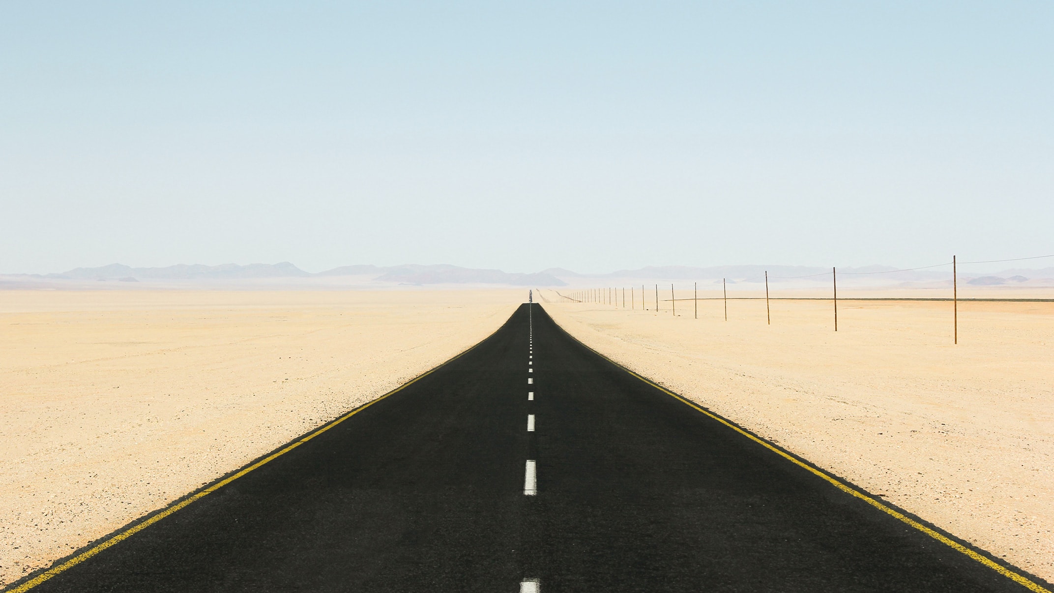 A photograph of a long, straight road going towards the horizon.