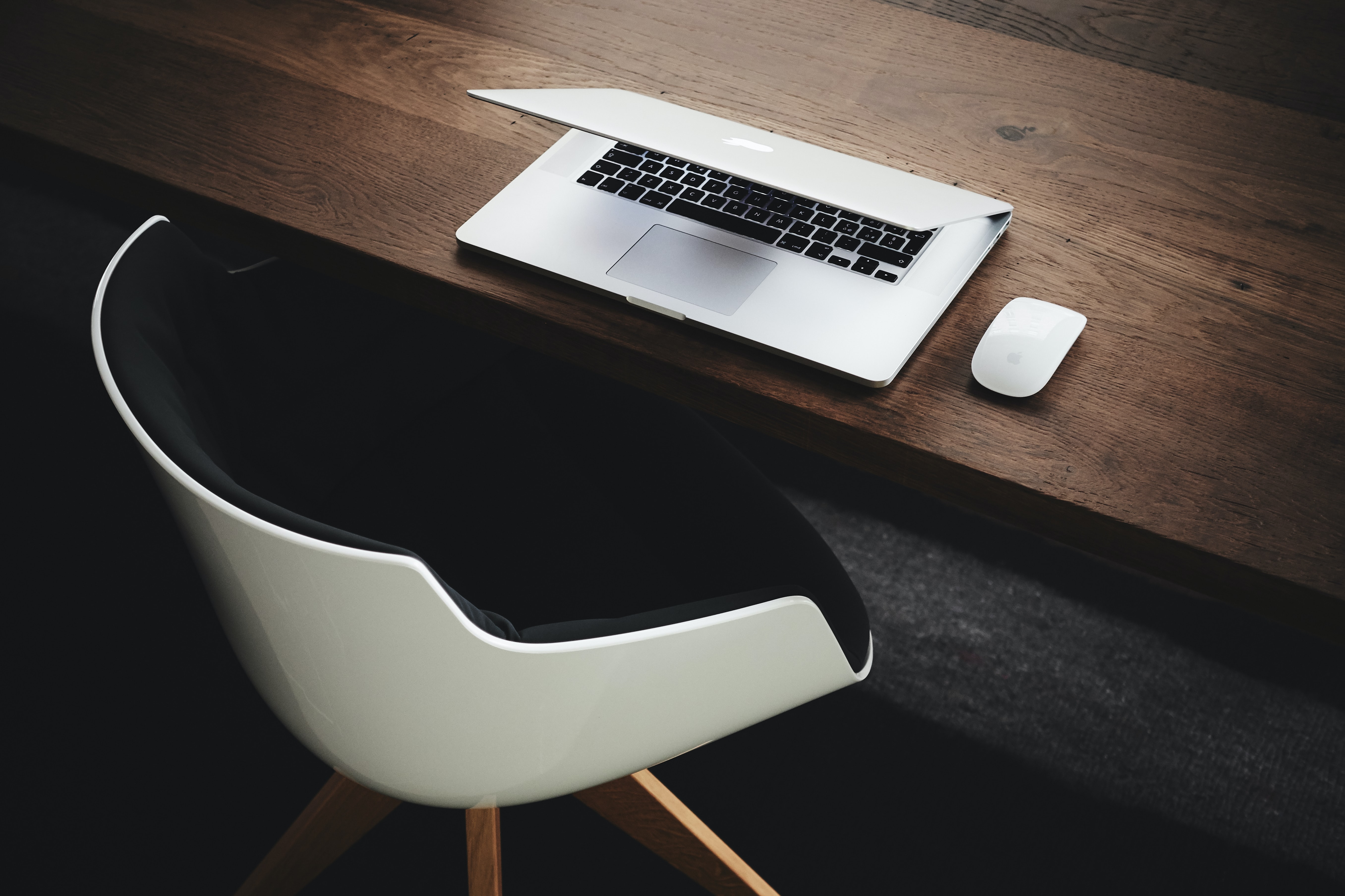 Half-closed laptop next to a mouse and in front of an empty office chair